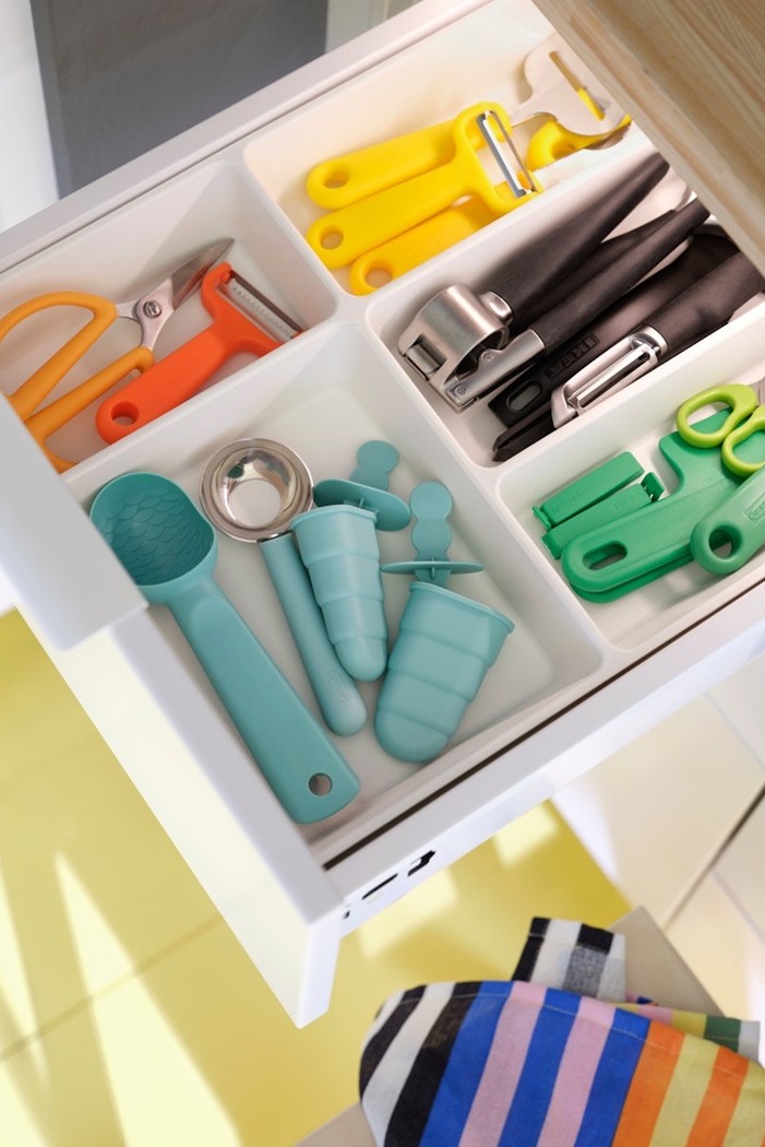 A cutlery tray in an open drawer with neatly organised utensils and kitchen tools.