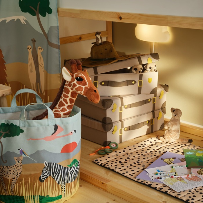 A SANDLÖPARE storage bag with a soft toy giraffe peeking out stands in the children’s room.