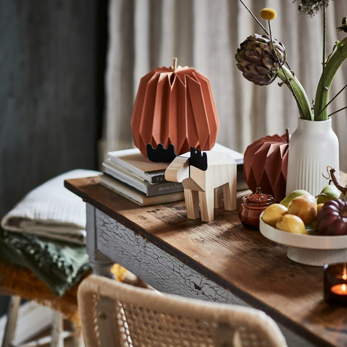 Decorative HÖSTAGILLE moose figure is placed on a wooden table, surrounded by paper pumpkins and other autumn decorations.