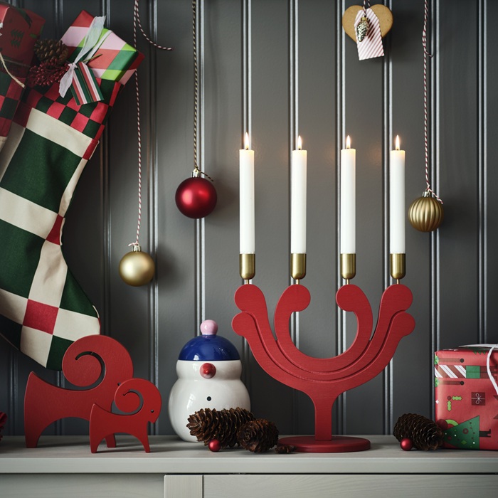 Праздничная рождественская композиция с красным деревянным подсвечником с четырьмя зажжёнными свечами, красной деревянной козой и другими украшениями.