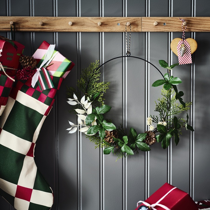 Стена в рождественском стиле украшена зелёным венком и чулок, подвешенных на деревянных крючках.