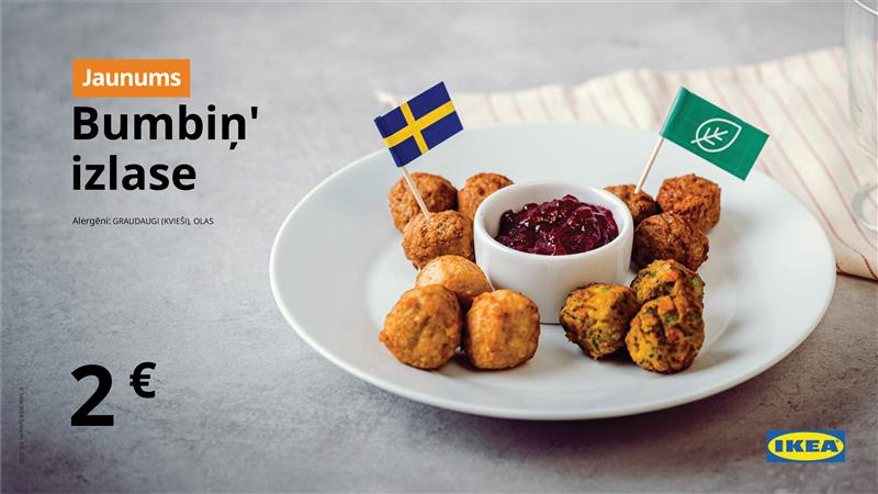 IKEA reklāmas attēls ar šķīvi, uz kura dažādas bumbiņas – gaļas, dārzeņu un augu –, pasniegtas ar brūkleņu mērci un dekorētas ar Zviedrijas un zaļo karodziņu. Teksts: “Jaunums – Bumbiņ' izlase. Cena: 2 €.”