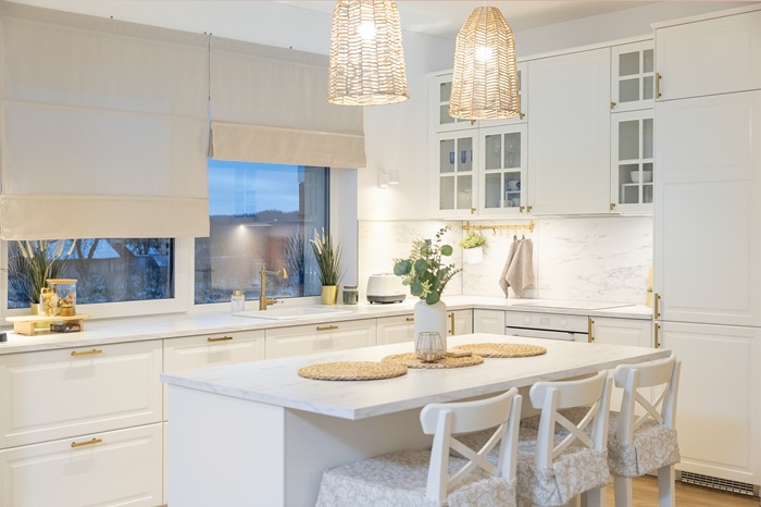 Modern white kitchen with an island, bar stools, pendant lamps and minimalist decor.