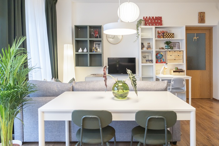 Contemporary living and dining area with a white table, green chairs and a grey sofa.