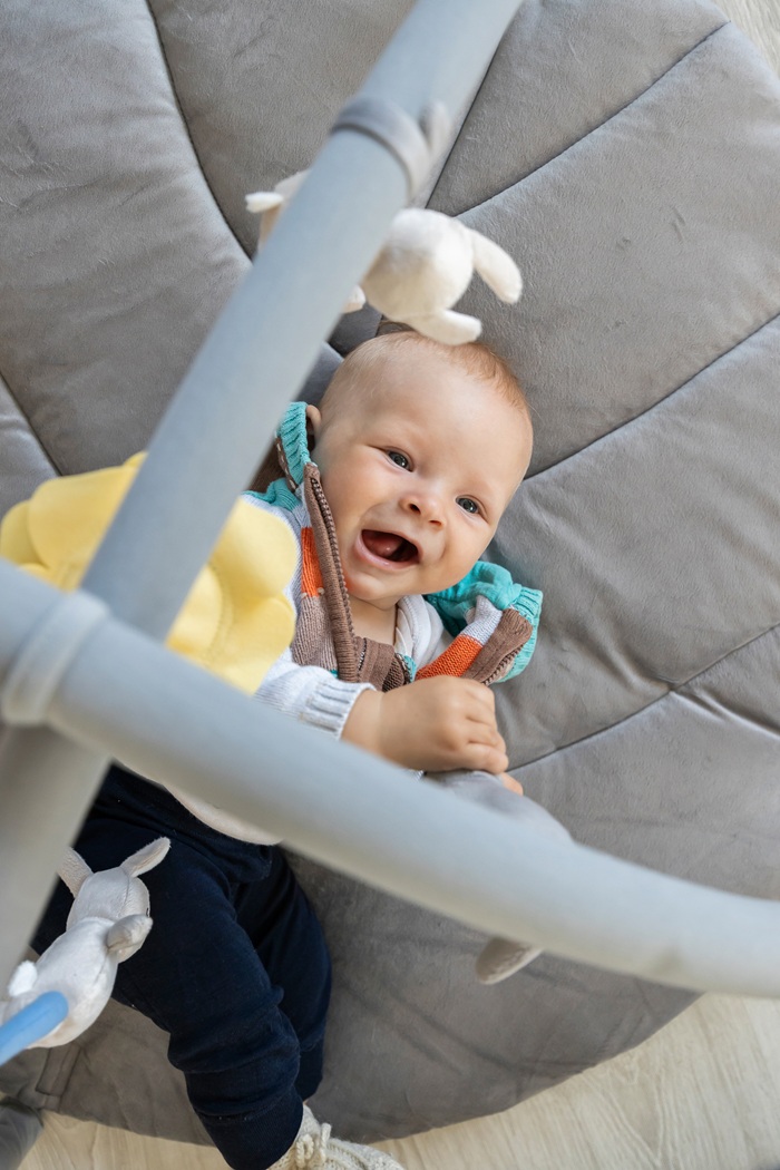 Giggling baby on a grey play mat.
