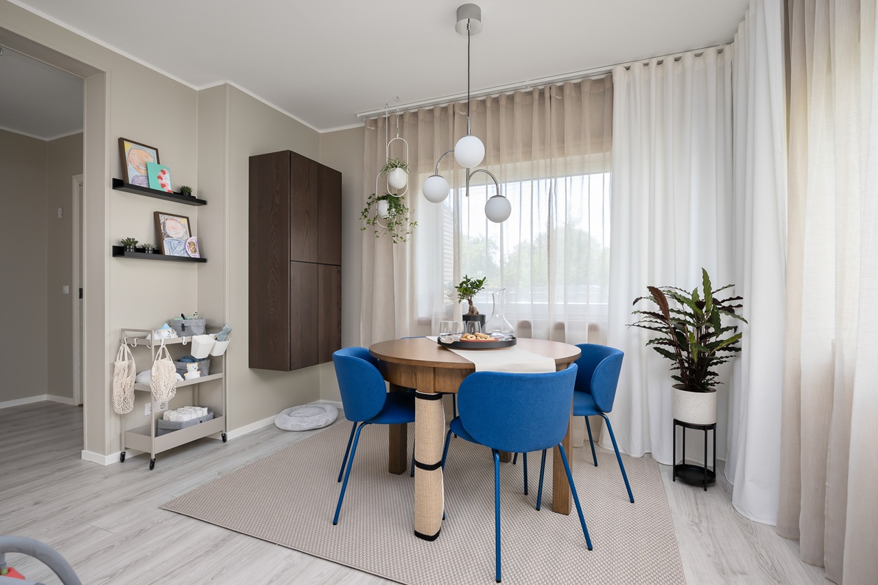 Spacious dining area with a round table, bold blue chairs and a dark brown METOD wall cabinet on the wall.