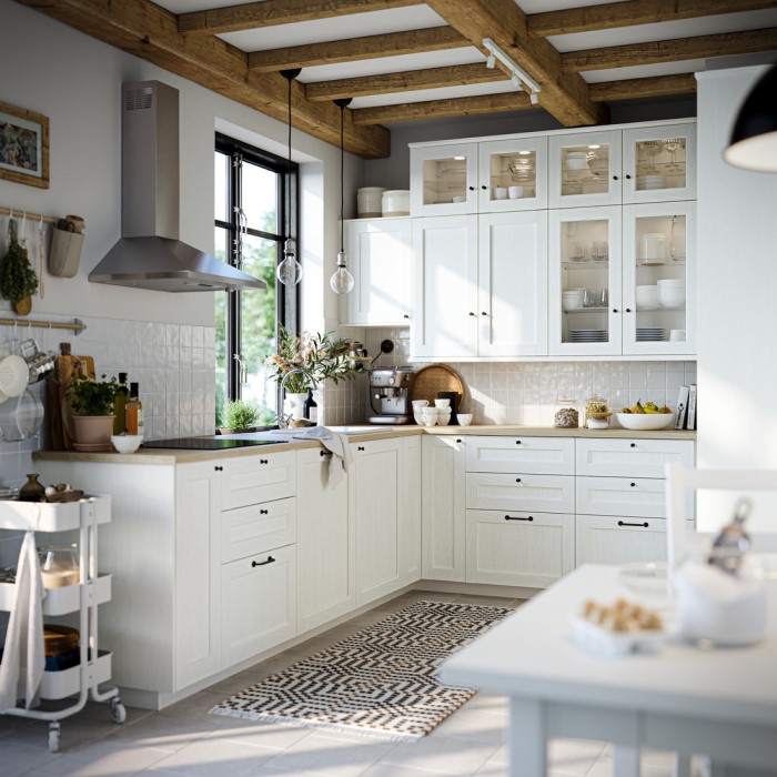 A bright, modern METOD kitchen featuring white cabinets, wooden beams on the ceiling and a cosy, organised layout.