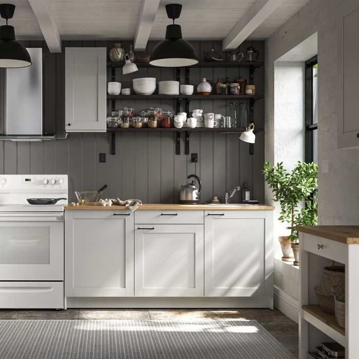A compact KNOXHULT kitchen combination, featuring white cabinets, wooden worktops and dark walls with open shelving.