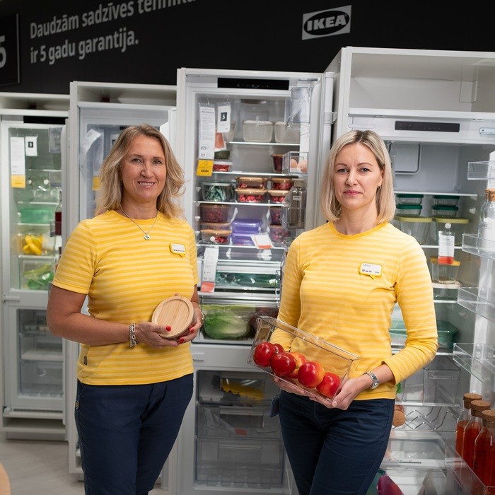 Two IKEA experts at a table in the store with dark grey GLADELIG tableware on a woven placemat.