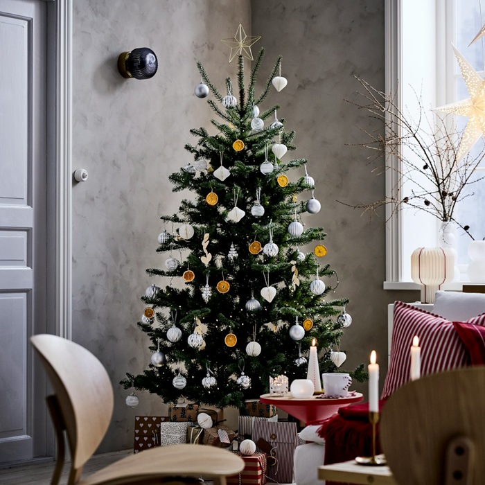 Telpa pelēkām sienām. Stūrī trīs koka krēsli un eglīte ar baltiem un oranžiem rotājumiem. Visapkārt sveces un svētku rotājumi baltā krāsā. Uz palodzes vāzē zari un pie loga piekārta STRÅLA zvaigzne.