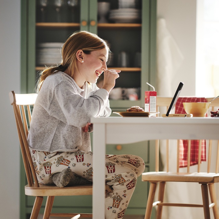 A child enjoying food at a white kitchen table.