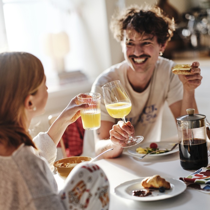 Two people smiling and sharing breakfast with juice and coffee.