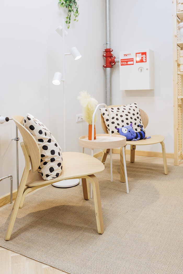 Jaukus kampelis dailės studijoje su mediniais krėslais, pagalvėlėmis ir kilimu.