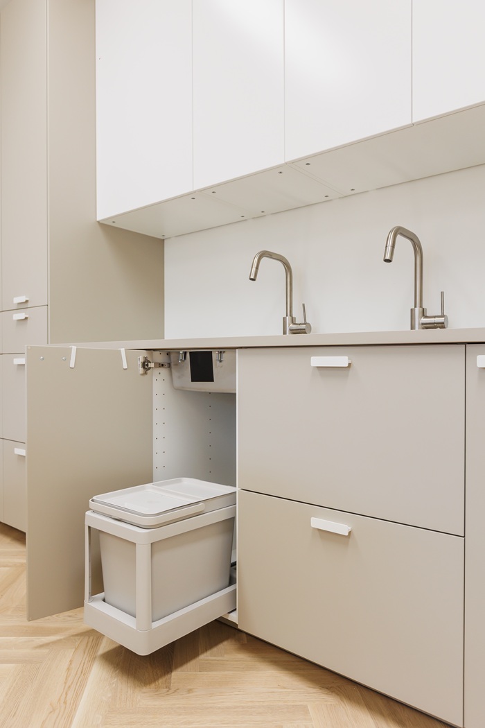 Dailės studijos virtuvėje, po plautuve, įrengtas ištraukiamas stalčius su smėlinės spalvos atliekų rūšiavimo dėže.