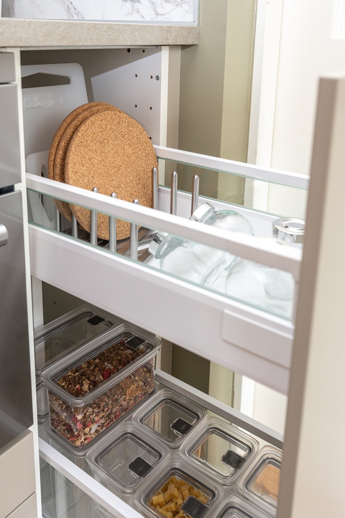 Külgvaade kahele üksteise kohal asuvale avatud köögisahtlile, mis on täis kööginõusid ja toidukarpe. 