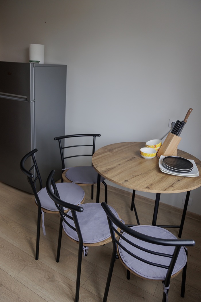 Virtuvės vaizdas iki pokyčių: mažas apvalus valgomojo stalas su keturiomis kėdėmis.