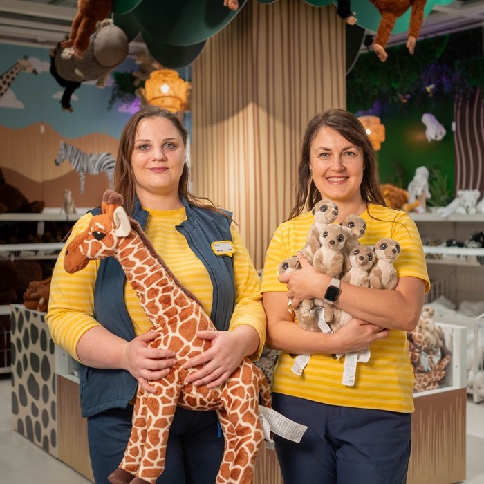 Divas IKEA ekspertes pie galda veikalā ar tumši pelēkiem GLADELIG traukiem uz pīta paliktņa.