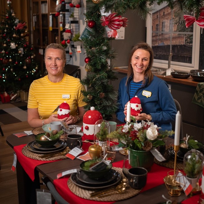 Two IKEA experts at a table in the store with dark grey GLADELIG tableware on a woven placemat.