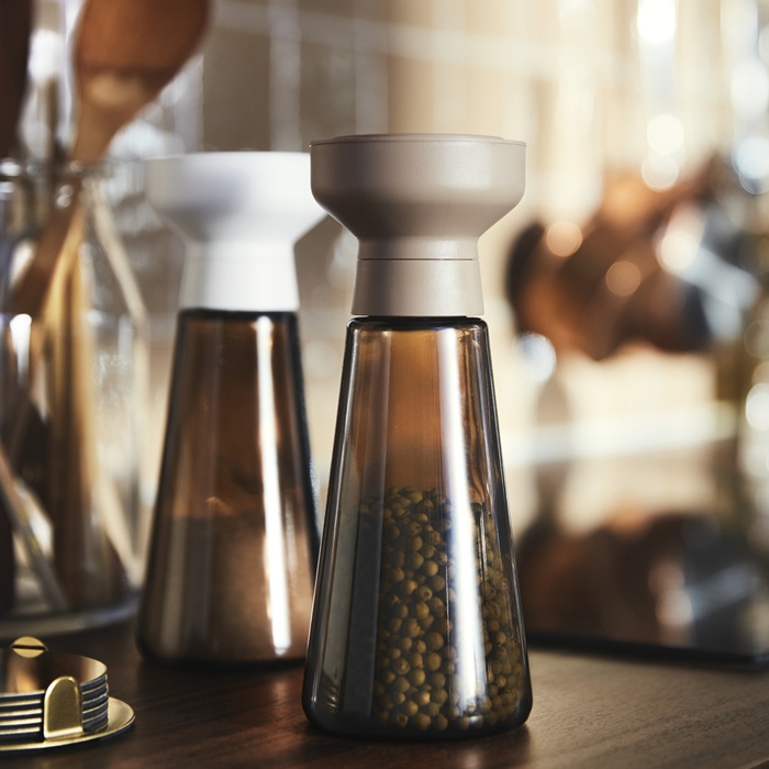 Two HALVTOM spice jars made of brown glass arranged on a kitchen surface.