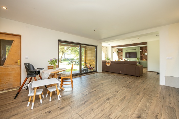 Piklik heledates toonides lastetuba. Esiplaanil paremas servas on valge kummut ja selle kohal ripuvad riidepuutorul värvilised riided. Tagapool on voodid.