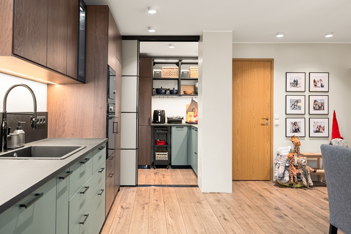 Heledates toonides lastetuba, kus pooleldi valge ja pooleldi beebisinise seina ees on sinise voodipesuga voodi. Voodijalutsis on mänguasjakast ja toa seinal on mööblit täis nukumaja. Garderoobiosa on kaugemas seinas.