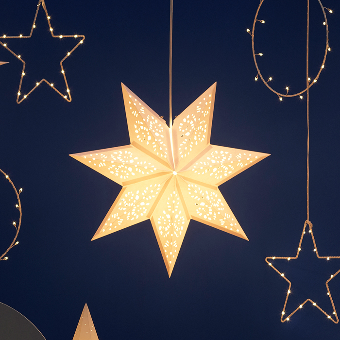 Soft-glowing STRÅLA lamp shade hanging against a dark blue background, surrounded by matching decorative lights from the same series.