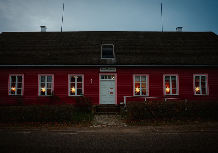 The Kihnu Museum with its red wooden high roof and white door, with the STRÅLA stars shining on its six symmetrically placed windows.