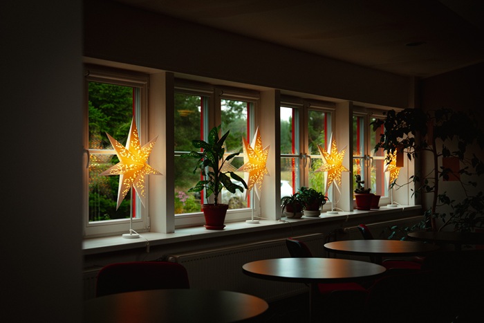 An interior space with round tables under the windows and STRÅLA stars shining on the windowsills.