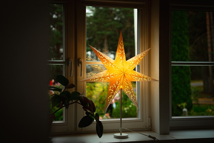 A white-framed window with a STRÅLA star and green plants on the windowsill.
