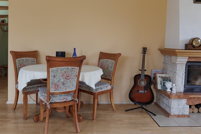 Гостиная до преображения: зелёный диван с розовыми подушками и кресло у деревянного журнального столика.