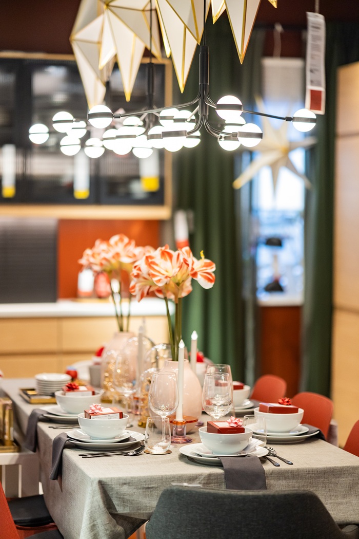 A decorated holiday table with candles, glass domes and pink floral arrangements, set in a contemporary dining area.