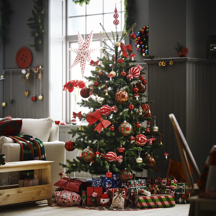A beautifully decorated Christmas tree, surrounded by wrapped presents and festive ornaments in red, green and gold.