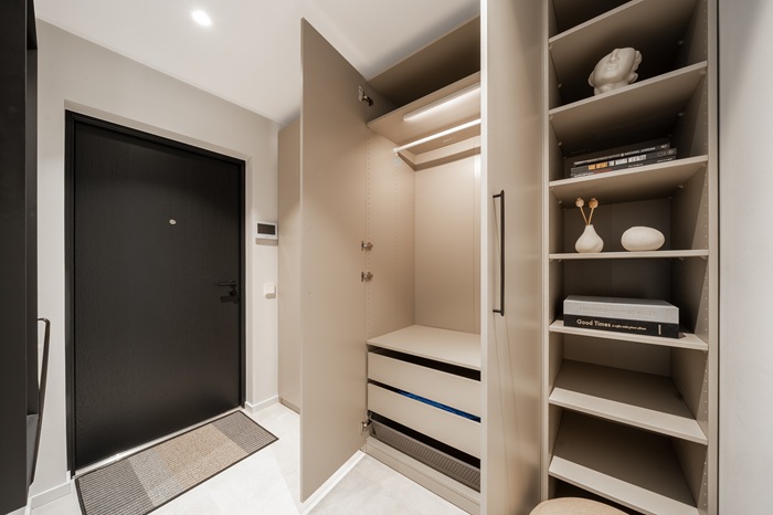 A hallway with a matte black door and light gray built-in shelving. Organized storage is visible through the open doors.