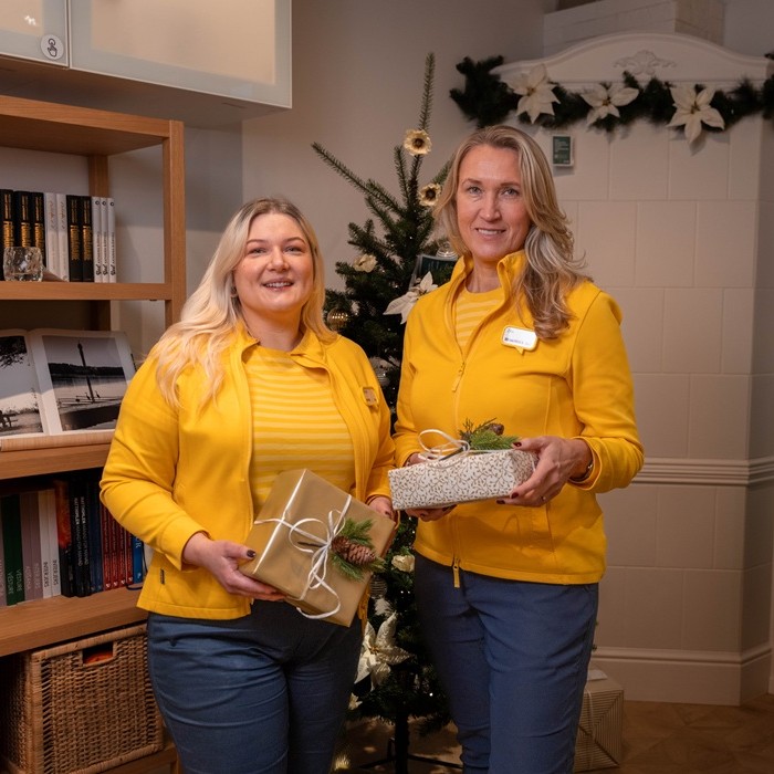 Divas IKEA ekspertes pie galda veikalā ar tumši pelēkiem GLADELIG traukiem uz pīta paliktņa.