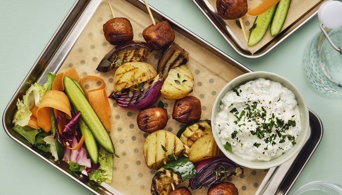 Vaade ülalt: kandik erinevate grillitud köögiviljadega, mis on vardas, ja kausike kastmega.