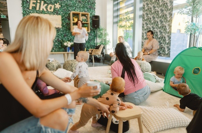 A table with Christmas treats, a steaming fruit drink in a white mug, a carafe, a bottle, candles.