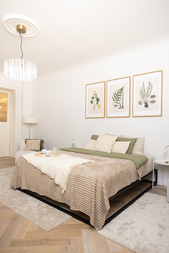 Guļamistaba ar divvietīgu gultu, neitrālu tekstilu, sienas mākslas darbiem un griestu lampu.