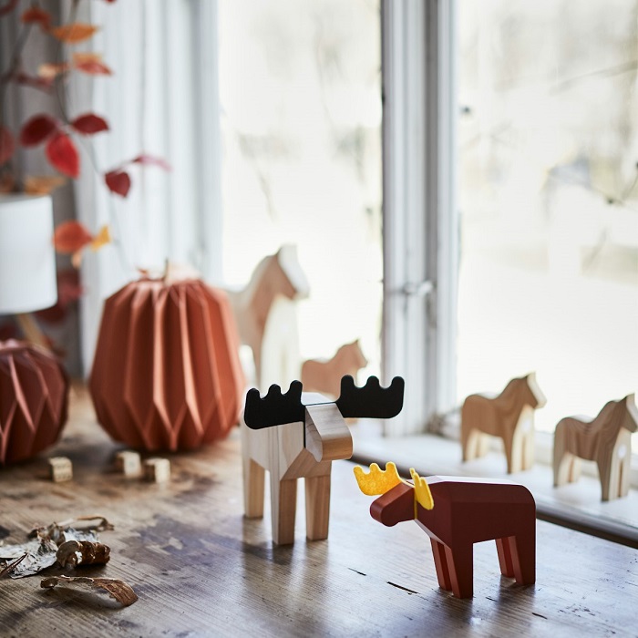 A rustic table adorned with HÖSTAGILLE decorations of pumpkins and a moose, and a HÖSTAGILLE serving stand with fruit.