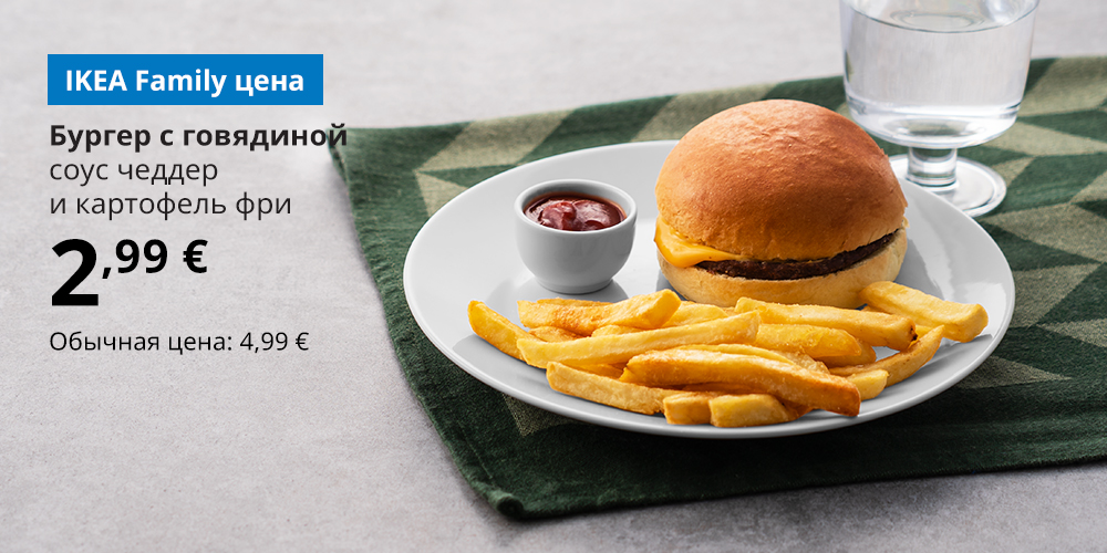Бургер с говядиной с картофелем фри и миской кетчупа на белой тарелке, рядом стакан воды. На синем блоке белый текст: «Бургер с говядиной, соусом чеддер и картофелем фри. 2,99 €. Обычная цена 4,99 €».