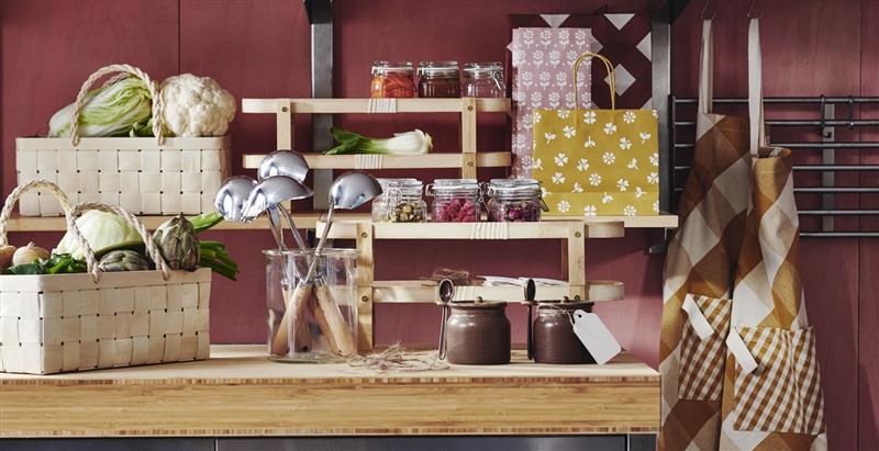 A kitchen where a table and shelves are adorned with KÖSSEBÄR items, like jars, baskets, tea towels, aprons, and more.