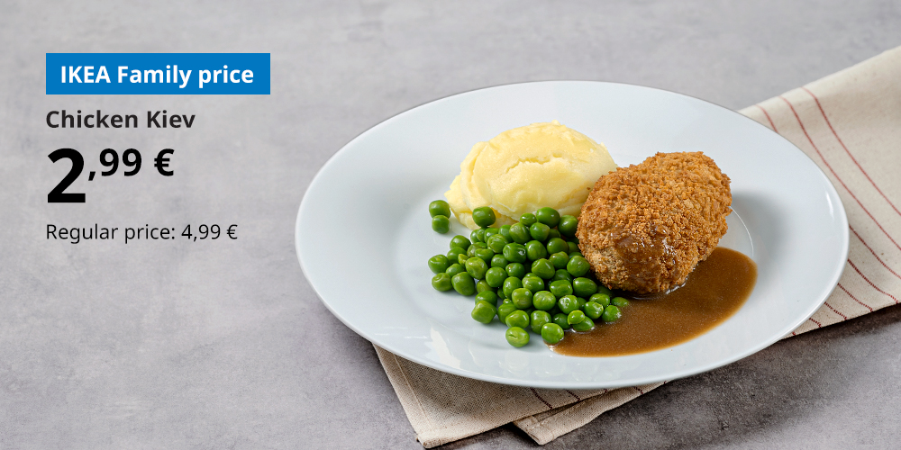 Chicken Kiev with mashed potatoes, peas and gravy on a white plate, placed on a grey countertop on top of a striped tea towel. In the top left corner, the IKEA Family price of 2,99 € is shown, with the regular price of 4,99 €.