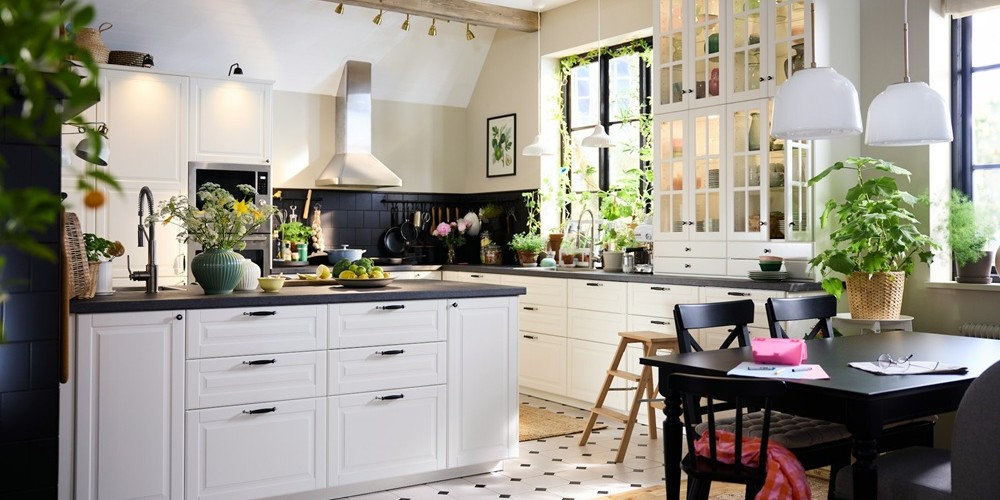 Большая кухня в традиционном стиле с белыми фасадами BODBYN, с кухонным островом и обеденной группой из тёмного дерева.